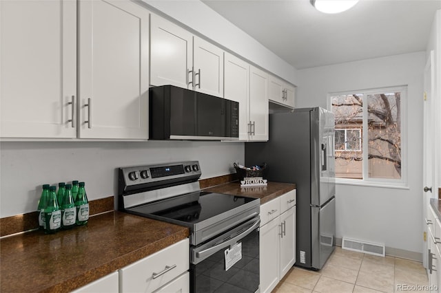 kitchen featuring appliances with stainless steel finishes, light tile patterned floors, and white cabinets