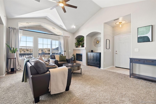 living room featuring light colored carpet, visible vents, baseboards, a ceiling fan, and a tiled fireplace