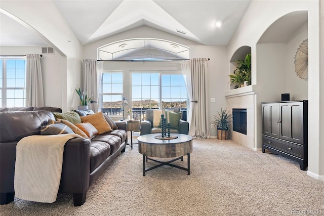 living room with lofted ceiling, a tiled fireplace, visible vents, and carpet flooring