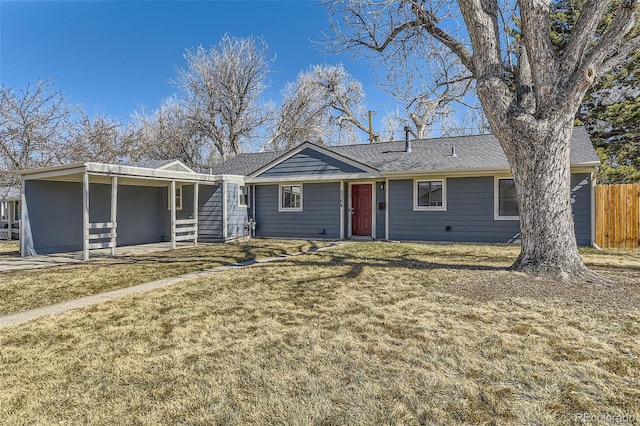 ranch-style home featuring a shingled roof, a front yard, and fence