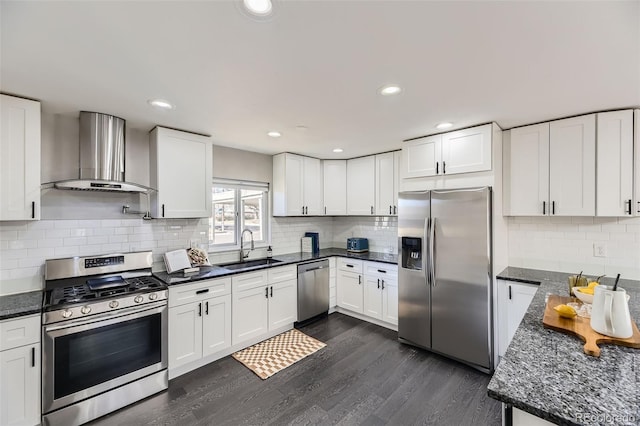 kitchen featuring dark wood-style floors, stainless steel appliances, wall chimney range hood, white cabinetry, and a sink