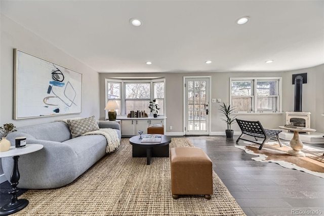 living room featuring recessed lighting, a wood stove, plenty of natural light, and wood finished floors