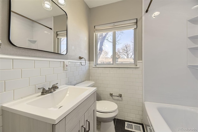 bathroom featuring visible vents, wainscoting, toilet, vanity, and tile walls