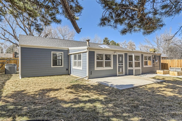 rear view of house with a lawn, roof with shingles, fence, cooling unit, and a patio area