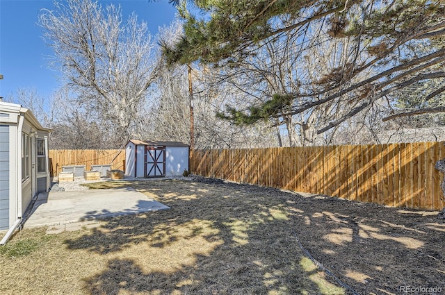 view of yard featuring a patio area, a fenced backyard, a storage unit, and an outbuilding