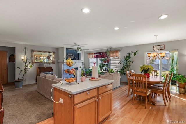 kitchen featuring pendant lighting, ceiling fan with notable chandelier, a center island, and light hardwood / wood-style flooring