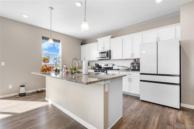 kitchen with a kitchen island with sink, hardwood / wood-style flooring, dark stone counters, white cabinetry, and appliances with stainless steel finishes