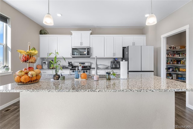 kitchen with white cabinetry, appliances with stainless steel finishes, decorative light fixtures, and dark hardwood / wood-style floors