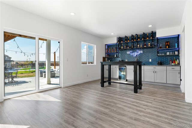 bar with white cabinetry, tasteful backsplash, and light wood-type flooring