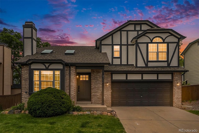 english style home featuring a garage and a lawn