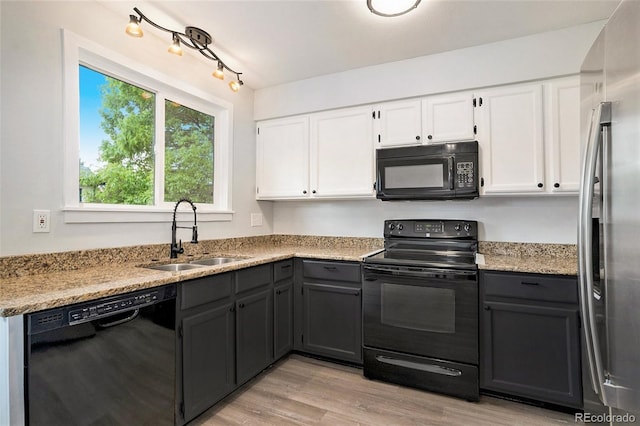 kitchen with black appliances, white cabinets, sink, light hardwood / wood-style flooring, and light stone countertops