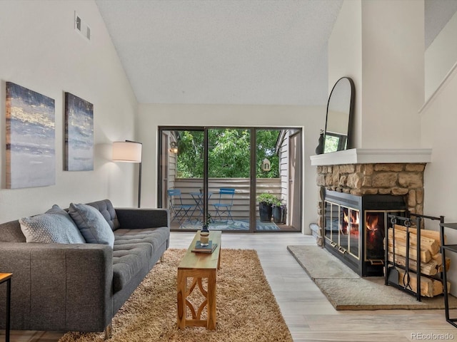 7379 S Gore Range Rd Unit 304, Littleton, CO 80127 - living room with high vaulted ceiling, a stone fireplace, wood finished floors, and a textured ceiling