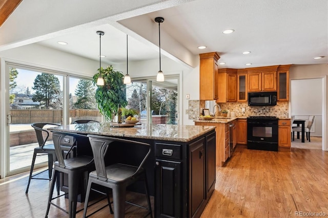 kitchen featuring sink, light stone counters, tasteful backsplash, black appliances, and pendant lighting