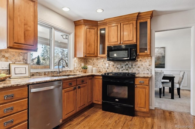 kitchen featuring light stone counters, light hardwood / wood-style flooring, black appliances, and sink