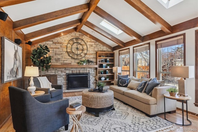 living room featuring a fireplace, vaulted ceiling with skylight, and light hardwood / wood-style flooring