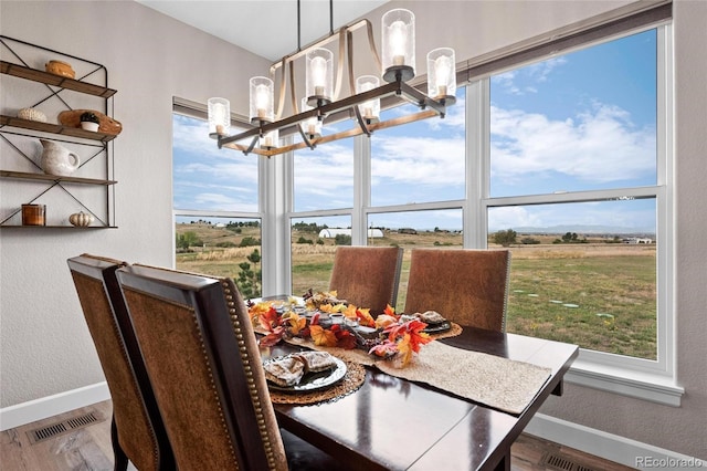 dining space with an inviting chandelier, wood finished floors, visible vents, and baseboards