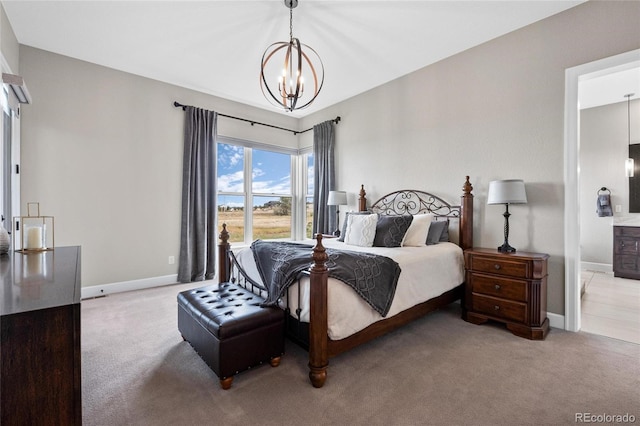 carpeted bedroom featuring baseboards, ensuite bath, and a chandelier