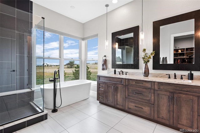 full bath with tile patterned flooring, a soaking tub, double vanity, and a sink