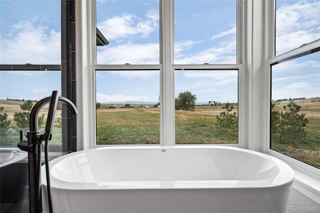 bathroom featuring plenty of natural light, a rural view, and a soaking tub