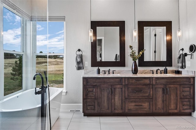 full bath with a sink, visible vents, double vanity, and a freestanding tub