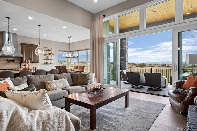 living area with recessed lighting, wood finished floors, a wealth of natural light, and a chandelier