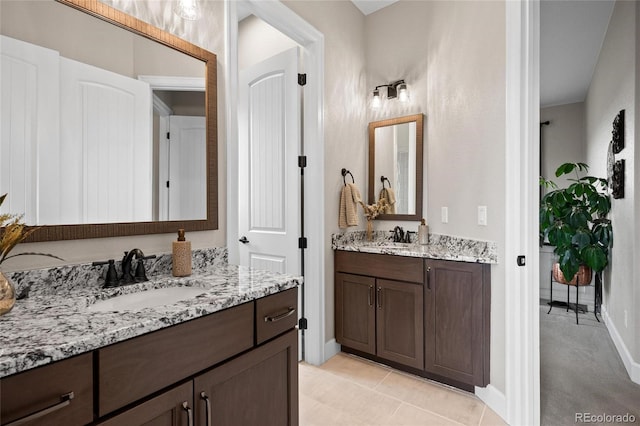 bathroom featuring a sink, baseboards, two vanities, and tile patterned floors