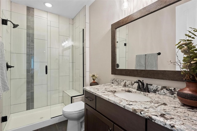 bathroom featuring tile patterned floors, vanity, toilet, and a shower stall