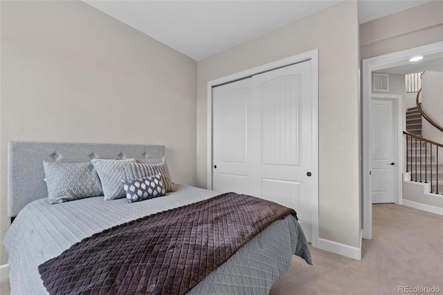 bedroom with a closet, baseboards, light colored carpet, and visible vents