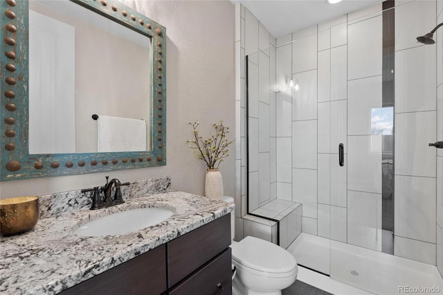 bathroom with vanity, a shower stall, and toilet