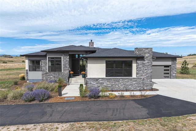 prairie-style home featuring an attached garage, stone siding, driveway, and a chimney