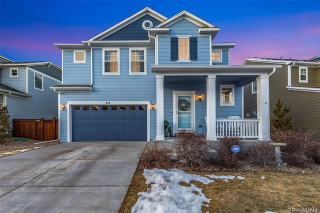 traditional-style house featuring an attached garage, fence, covered porch, and concrete driveway
