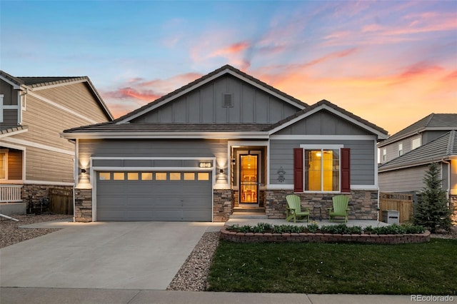 craftsman-style home featuring board and batten siding, concrete driveway, a garage, and stone siding