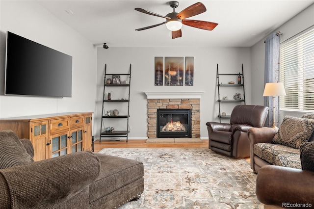 living area with a fireplace, a ceiling fan, and wood finished floors