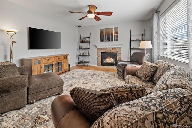 living room with wood finished floors, ceiling fan, a fireplace, and baseboards