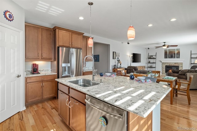 kitchen with stainless steel appliances, decorative light fixtures, brown cabinets, and a sink