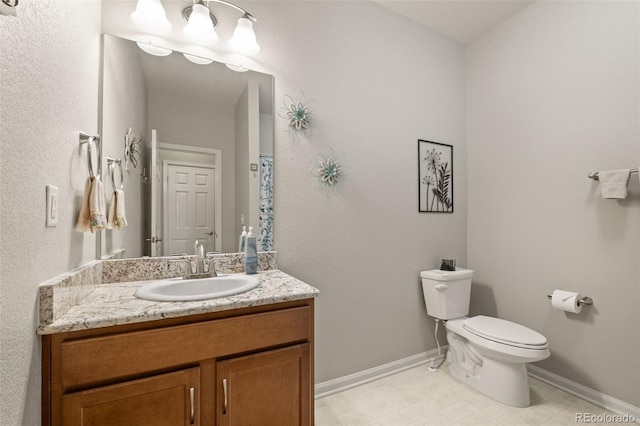 bathroom with toilet, vanity, and baseboards