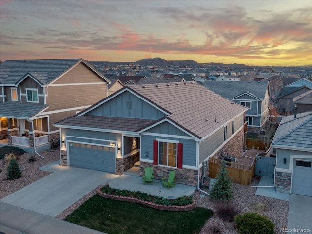craftsman inspired home with concrete driveway, a residential view, stone siding, board and batten siding, and a garage