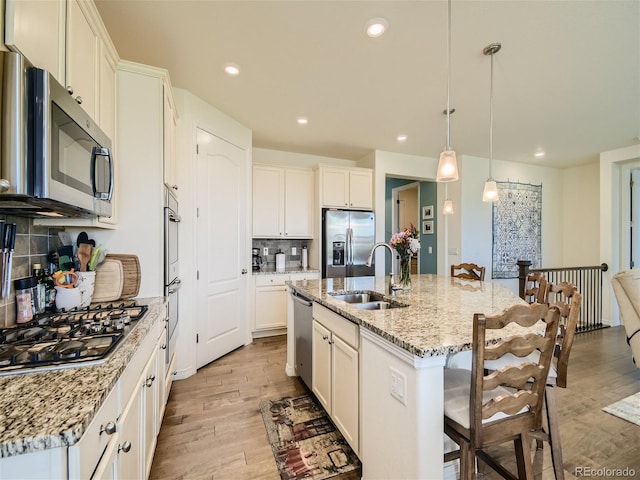 15347 Quince Cir, Thornton, CO 80602 - kitchen featuring stainless steel appliances, light wood-type flooring, backsplash, a sink, and an island with sink
