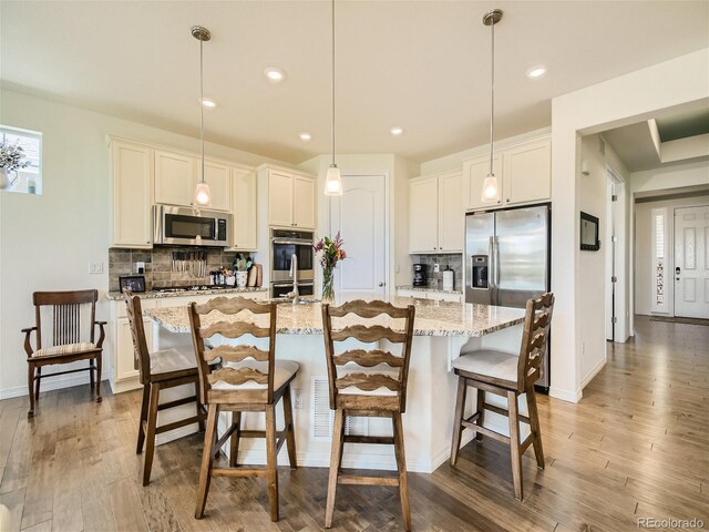 15347 Quince Cir, Thornton, CO 80602 - kitchen with appliances with stainless steel finishes, backsplash, wood finished floors, an island with sink, and recessed lighting