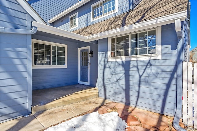 doorway to property with a shingled roof and a patio area