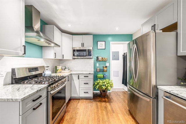 kitchen featuring wall chimney exhaust hood, white cabinetry, and stainless steel appliances