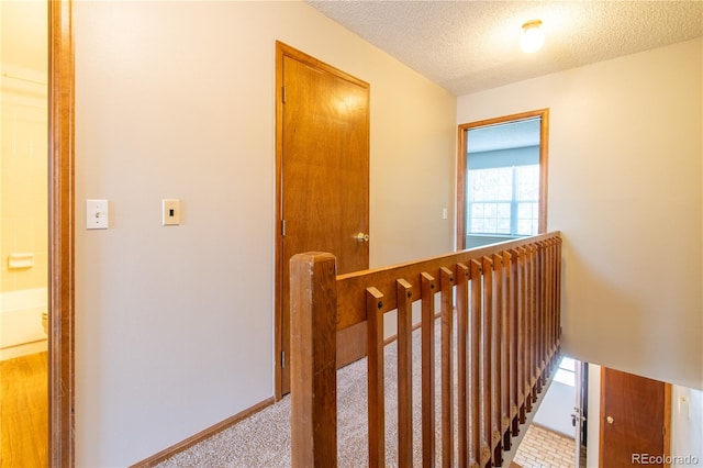 hall with light carpet and a textured ceiling