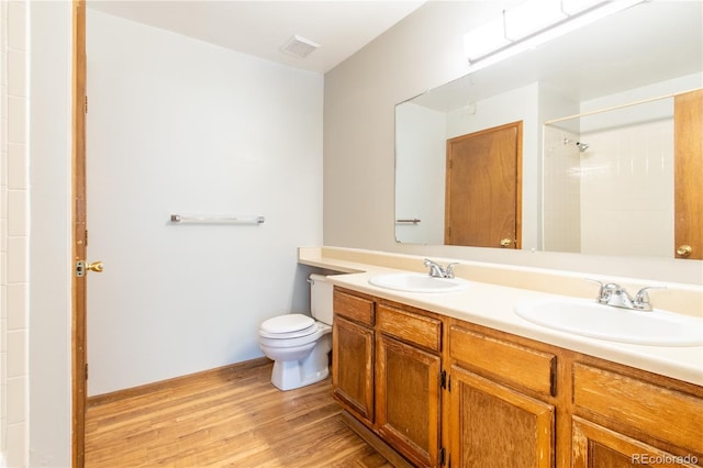 bathroom with wood-type flooring, walk in shower, vanity, and toilet