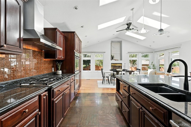 3608 S Newport Way, Denver, CO 80237 - kitchen featuring wall chimney range hood, a skylight, vaulted ceiling, backsplash, and stainless steel appliances