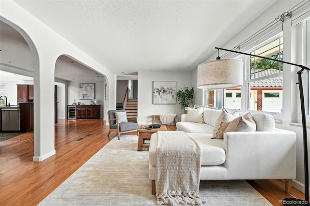 3608 S Newport Way, Denver, CO 80237 - living room with wine cooler, stairs, arched walkways, light wood-style floors, and a textured ceiling