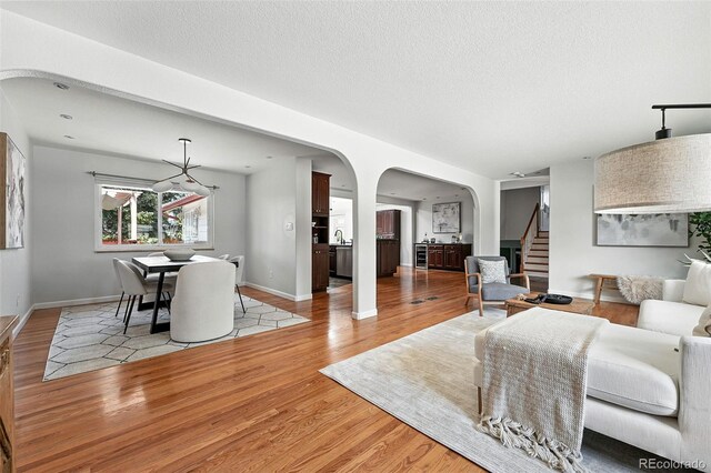 3608 S Newport Way, Denver, CO 80237 - living room featuring arched walkways, stairway, light wood-style flooring, and a textured ceiling