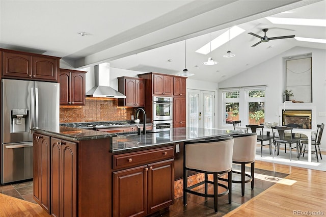 3608 S Newport Way, Denver, CO 80237 - kitchen featuring stainless steel appliances, wall chimney exhaust hood, vaulted ceiling, tasteful backsplash, and dark stone countertops
