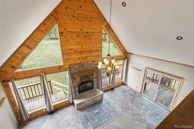 181 Sawmill Rd, Loveland, CO 80537 - unfurnished living room with a chandelier, a fireplace, wood walls, high vaulted ceiling, and stone finish floors