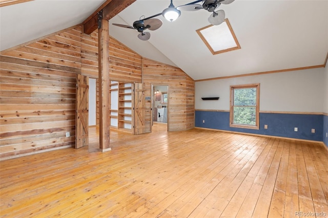 181 Sawmill Rd, Loveland, CO 80537 - unfurnished living room featuring ceiling fan, wood walls, hardwood / wood-style floors, and a skylight