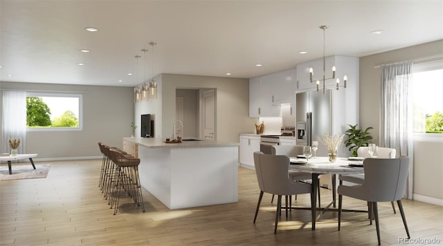 kitchen featuring pendant lighting, a center island with sink, and white cabinetry